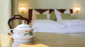 A white teapot with floral designs on a wooden table in a hotel room.