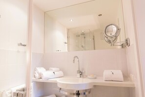 Un bagno moderno con uno specchio grande, un lavandino e una doccia.