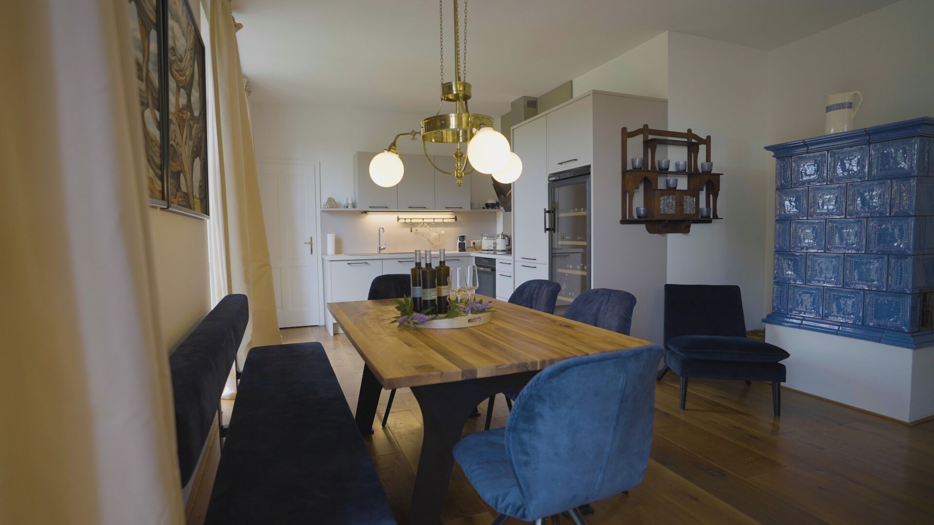 A dining area with a wooden table, blue chairs, and a chandelier.