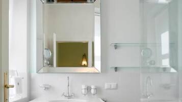 A bathroom with a white pedestal sink, a mirror above it, and a toilet.