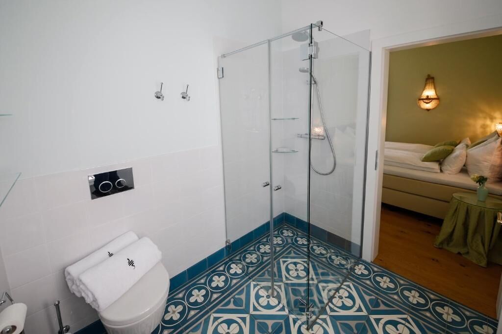 Une salle de bain avec une douche à parois de verre, des toilettes avec un abattant blanc et un carrelage décoratif.