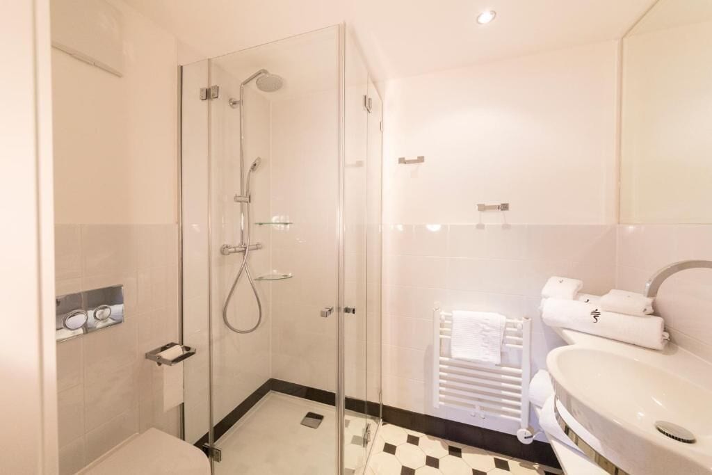 A modern bathroom with a glass-enclosed shower, a white sink, and a toilet.