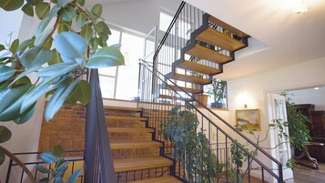 A modern staircase with wooden steps and metal railings, leading to a second floor.