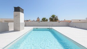 A rooftop swimming pool with clear blue water, surrounded by white tiled flooring and a low concrete wall. - Solaga - Alta (Málaga)