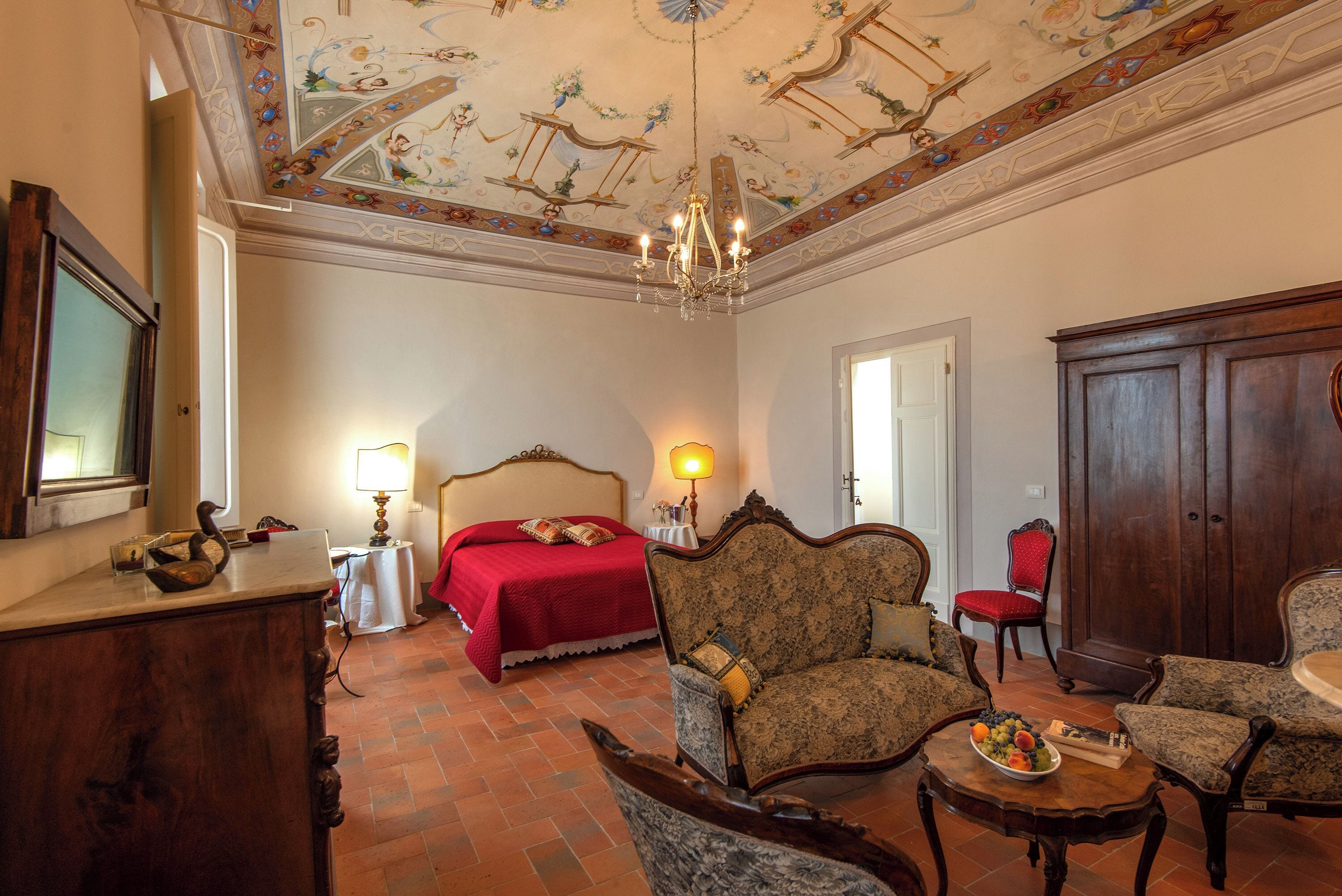 Quarto com uma cama, duas poltronas, um armário de madeira e um candelabro.