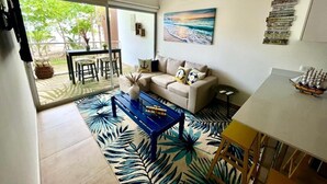 A living room with a sofa, coffee table, and a painting on the wall. - Stylish Oceanfront Condo 3205 | Playa Bejuco + Bright Design + Pool (Bejuco)