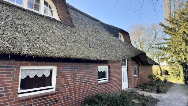 A traditional brick house with a thatched roof and a small garden. - Ferienwohnung im Reetdachhaus, Burhave (Butjadingen)