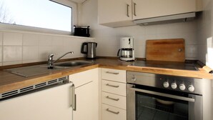 A compact kitchen with a sink, coffee maker, toaster, and oven. - Ferienwohnung im Reetdachhaus, Burhave (Butjadingen)