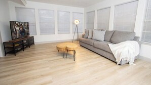 Ein Wohnzimmer mit Sofa, Couchtisch, Fernseher und Stehlampe.
