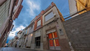 A narrow street with buildings on both sides, featuring a mix of residential and commercial properties. - Casa Pueblo Alzira (Alzira)