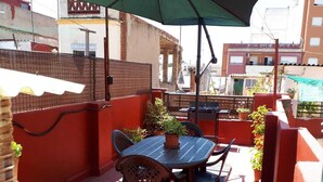 An outdoor patio with a table and chairs, a green umbrella, and potted plants. - Casa Pueblo Alzira (Alzira)