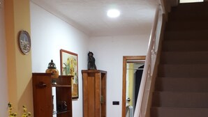 A hallway with a tiled floor, a wooden cabinet, a vase with flowers, and a staircase. - Casa Pueblo Alzira (Alzira)