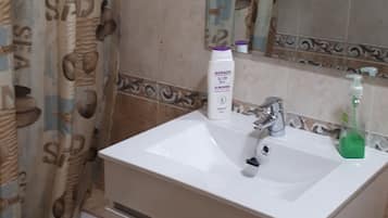 Een badkamer met een witte wastafel, een spiegel en een douchegordijn met een patroon.