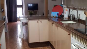 A kitchen with white cabinets, a tiled floor, and a stove.