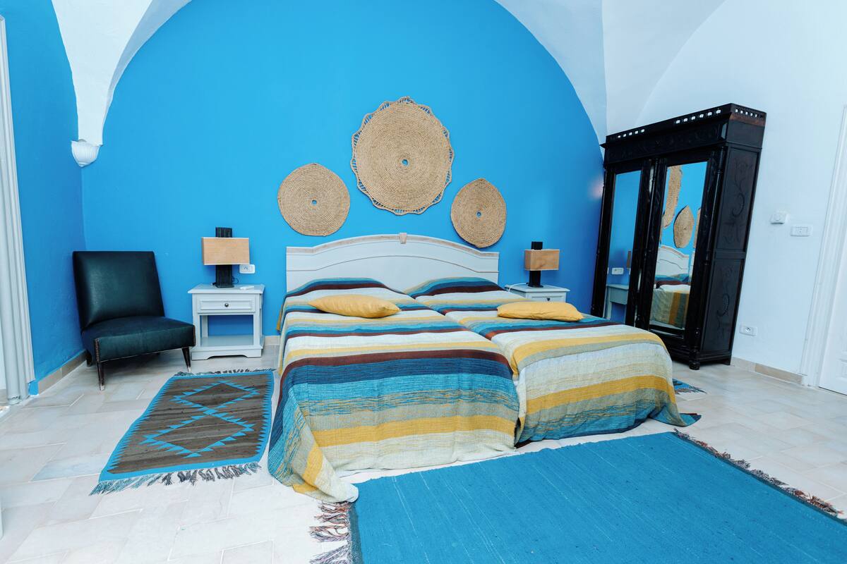 Une chambre à coucher avec un grand lit, une chaise, une table de chevet et une armoire.