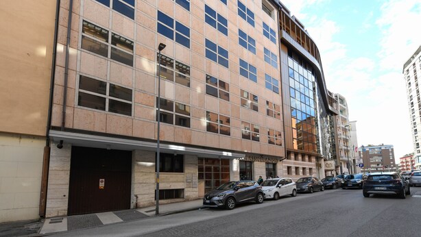 En bygning med flere etager, moderne facade, store vinduer og indgang i stueplan.