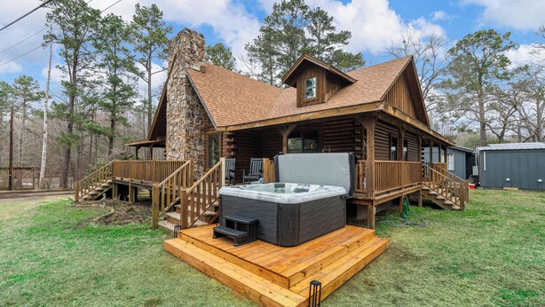 Eine Blockhütte mit Whirlpool und Holzterrasse.