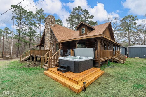 Relax at this lakefront log cabin on private Emerald Isle, designed for easy outdoor living. Enjoy the hot tub, paddle out with kayaks and canoes, gather around the fire pit, or grill and unwind by the water.