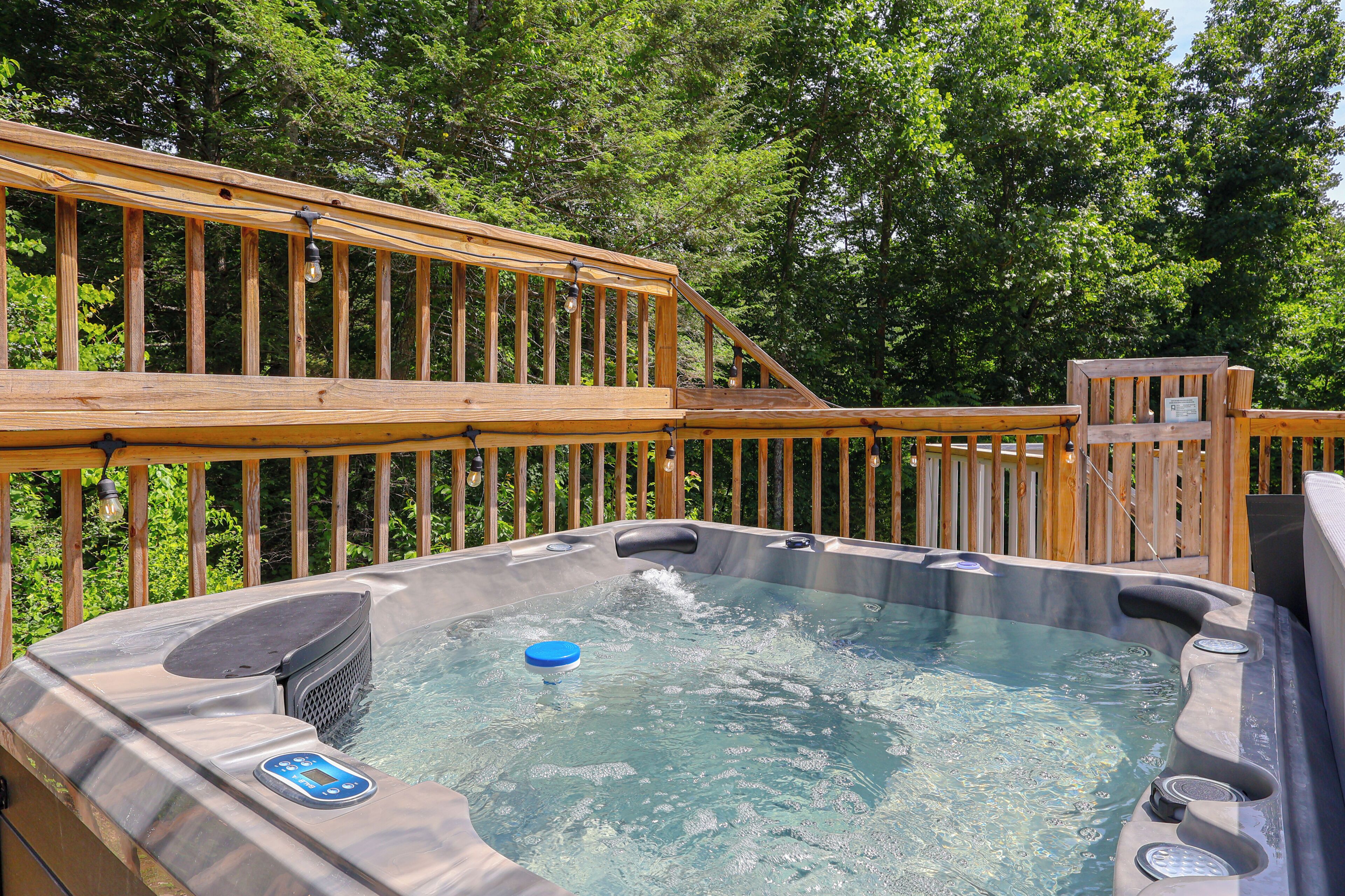 A hot tub with a wooden deck, surrounded by trees.