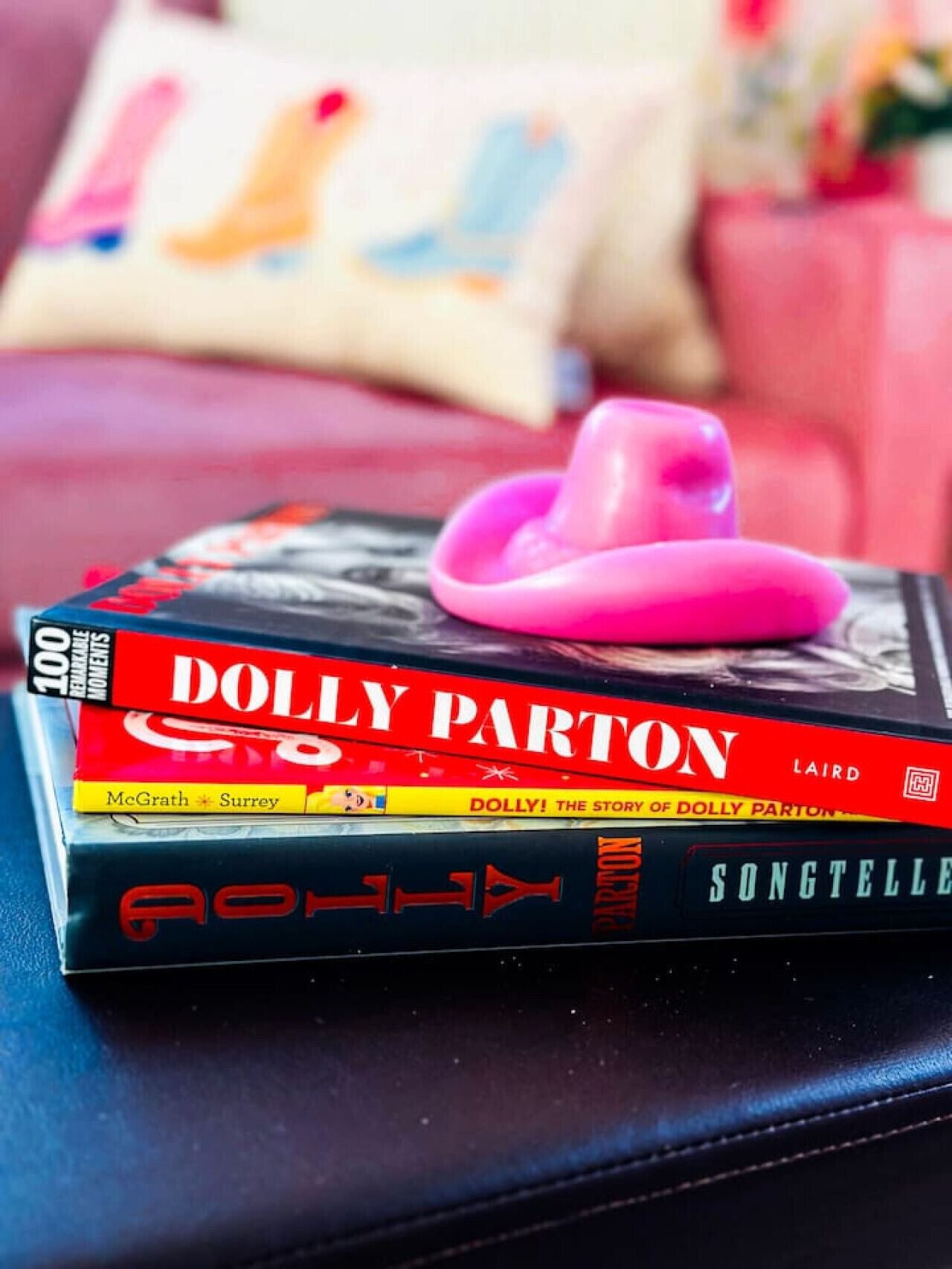 Une pile de livres sur une surface, avec un objet rose posé dessus.
