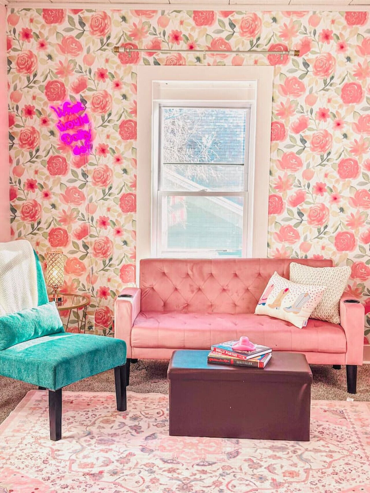 A cozy living room with a pink sofa, teal armchair, and a coffee table.