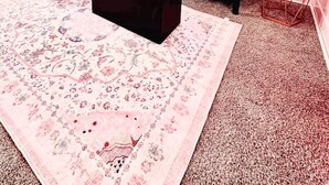 Un salon décoré dans des tons de rose, avec un fauteuil bleu, un canapé rose et un tapis à motifs.