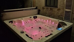 A hot tub with pink LED lights, a control panel, and a window with shutters. - Charming cottage between forest and relaxation with spa and WIFI (Ville-sur-Illon)