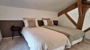A bedroom with two beds, a nightstand, and a wooden beam structure. - Charming cottage between forest and relaxation with spa and WIFI (Ville-sur-Illon)