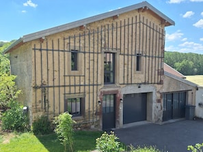 Un edifici de dues plantes amb garatge, una finestra petita i una porta.
