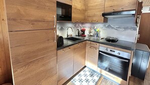 Eine Küche mit Holzausstattung, einem Edelstahlbackofen und einer Mikrowelle.