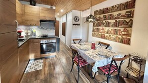 Eine moderne Küche mit Holzausstattung, einem eingebauten Backofen und einem Essbereich mit Tisch für vier Personen.