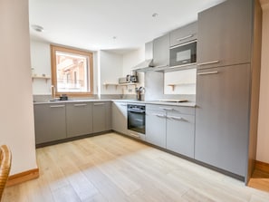 A modern kitchen with grey cabinets, a built-in oven, microwave, and a window with a view.