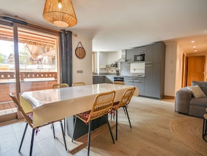 A modern kitchen with a dining area, a sofa, and a view of the outdoors.