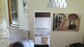 A living room with a sofa, a dining table with chairs, a kitchen in the background, and a painting on the wall. - Detached house with two entrances and parking space on private road, convenient and new (Gallipoli)