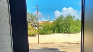 A view through a window of a parking lot with a building in the background, a power line, and some greenery. - Detached house with two entrances and parking space on private road, convenient and new (Gallipoli)