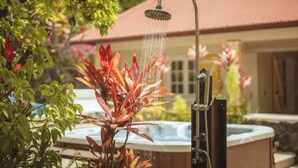 A hot tub with a showerhead in a garden setting. - Villa LONTAN (Entre-Deux)