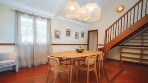 A dining area with a round wooden table, four chairs, a bench, and a staircase. - Villa LONTAN (Entre-Deux)