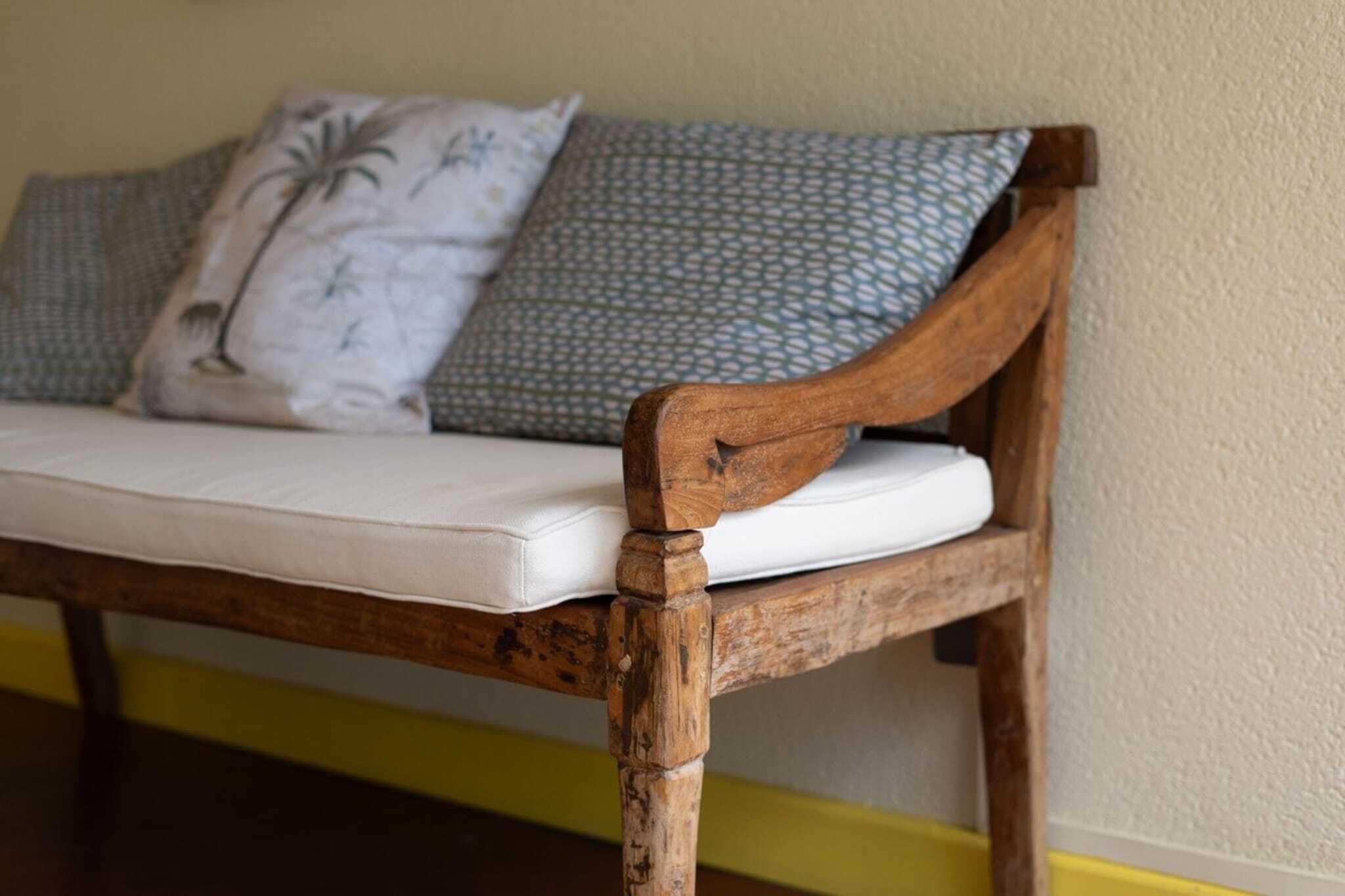 Een houten bank met een matras en gestreepte kussens.