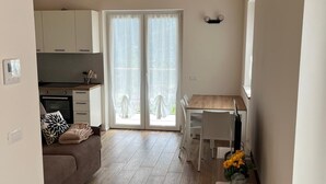A modern living space with a wooden ceiling, a kitchen area, a dining table, and a sofa. - Casa Bice - A new apartment in the center of Tesino (Castello Tesino)