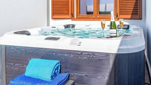Lämminvesiallas, jossa on kaksi puista sälekaihdinta, pullo Arestel-viiniä ja kaksi lasia altaan reunalla.