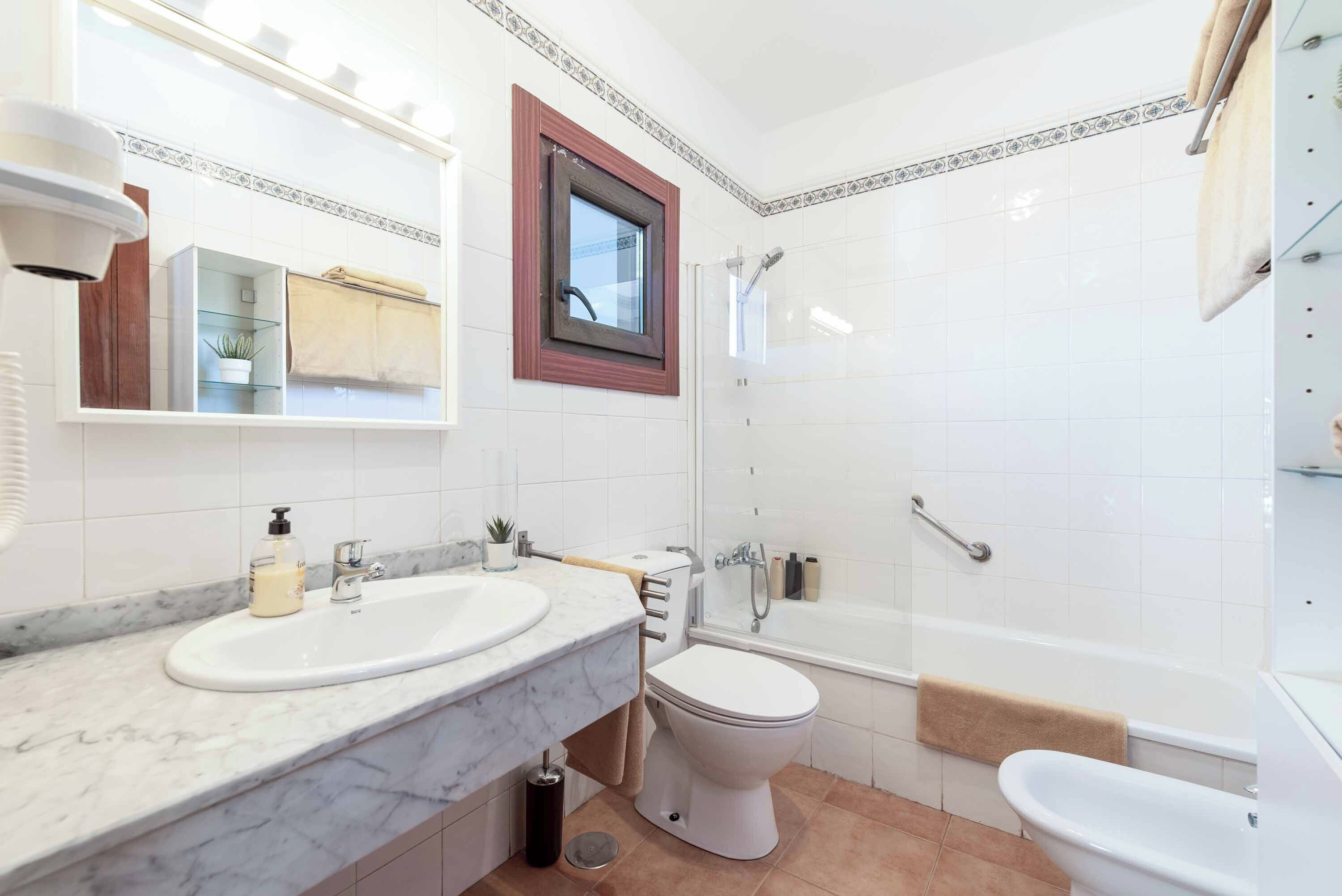 A modern bathroom with a marble sink, a toilet, a bathtub, and a shower.