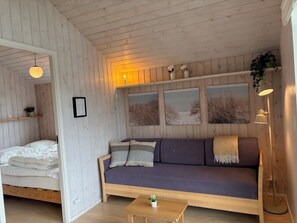 Een knus ingerichte kamer met houten plafond, een bank, een bed en een klein tafeltje.