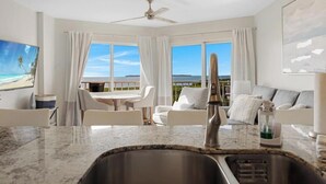 Une chambre d’hôtel moderne dotée d’un coin cuisine, d’un espace repas et d’un balcon avec vue.