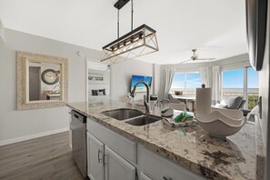 A modern kitchen with granite countertops, a double sink, and a hanging light fixture.