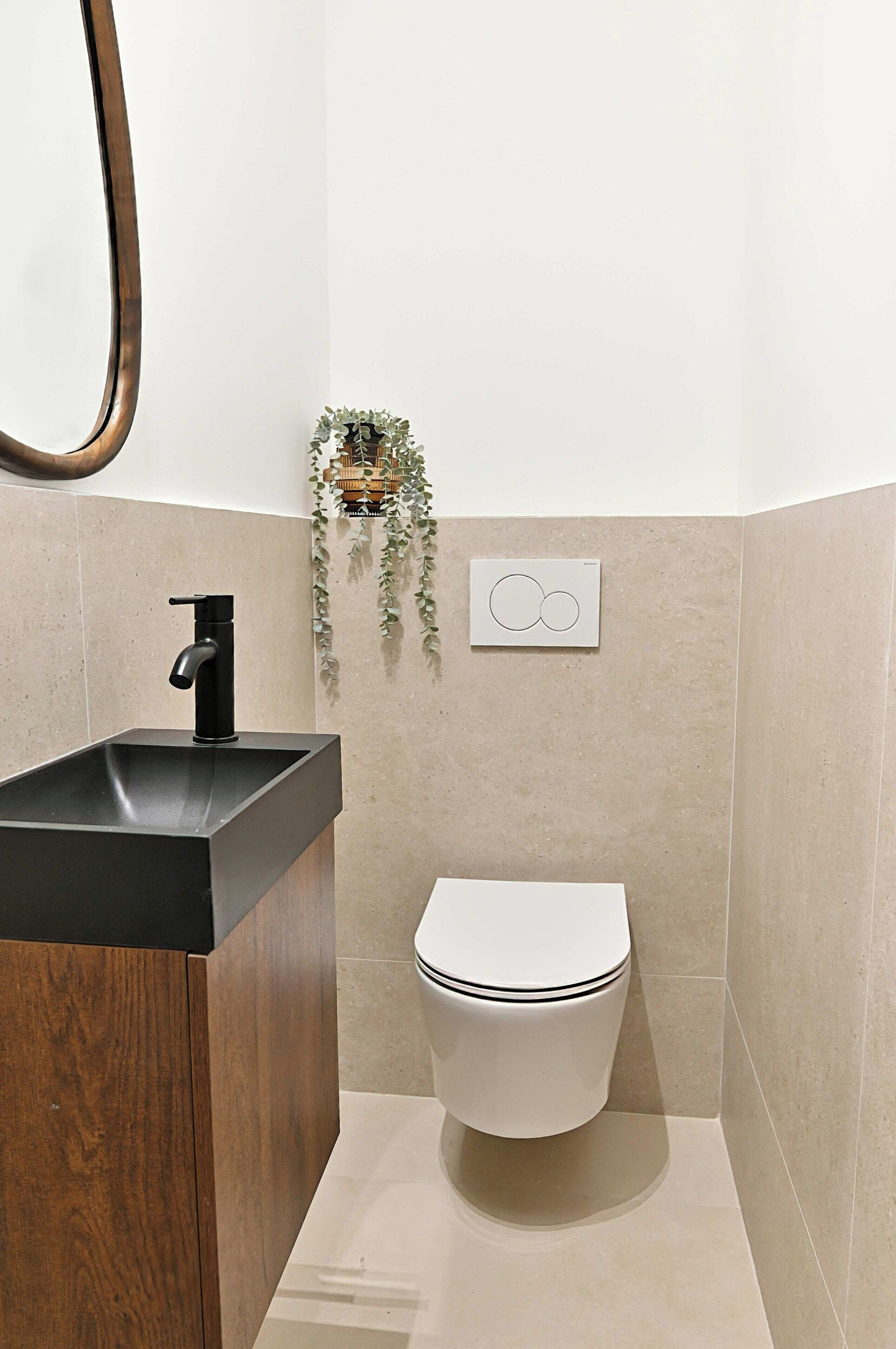 A bathroom with a black sink, white toilet, and a mirror.