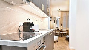 Eine moderne Küche mit Marmorarbeitsplatte, integriertem Backofen und einer Kaffeemaschine.