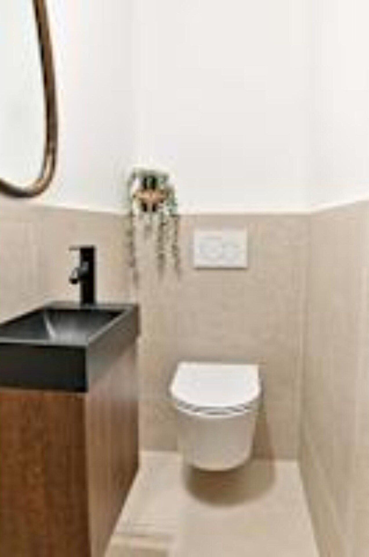 A small bathroom with a black sink, a white toilet, and a mirror on the wall.
