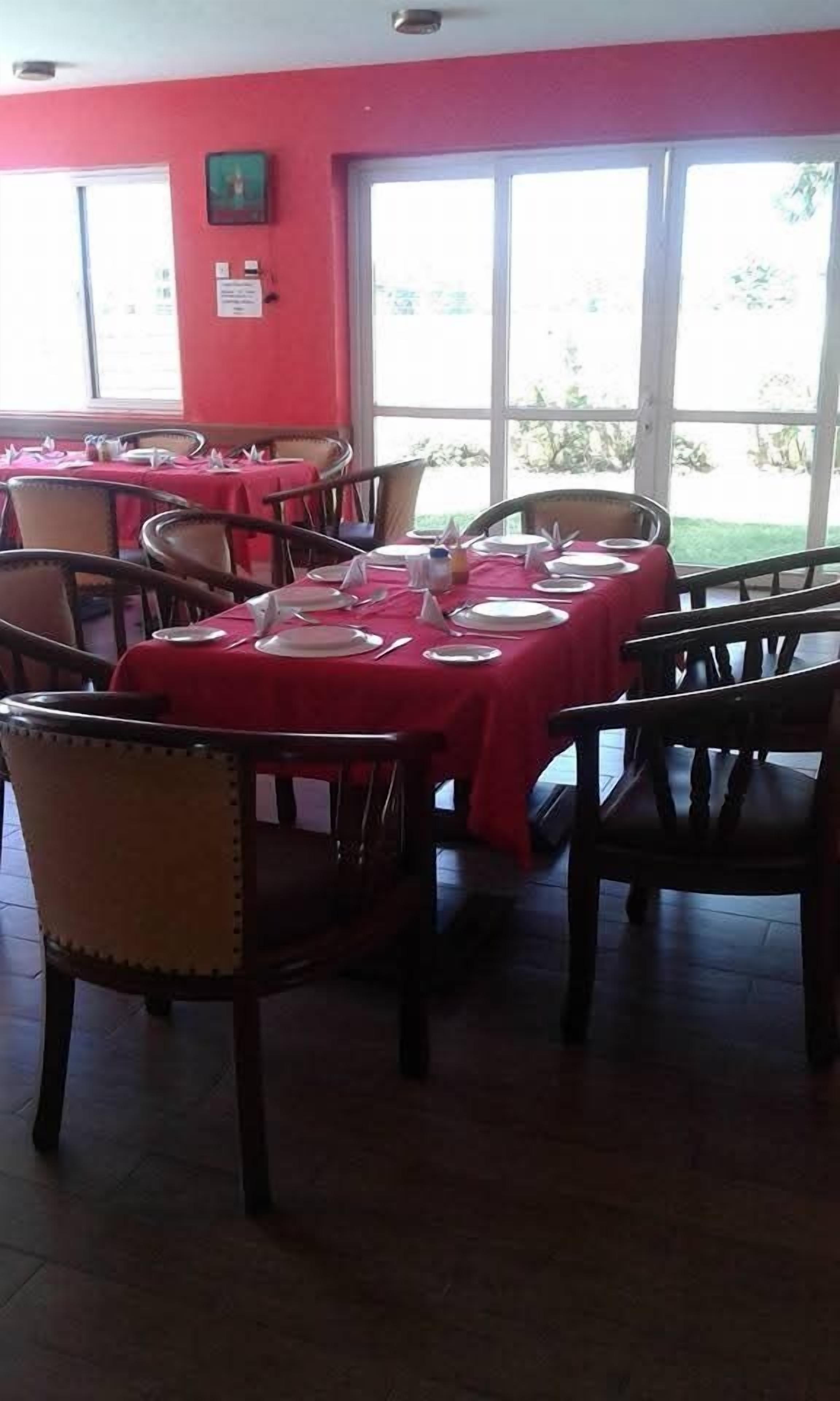 A dining area with tables set for service, chairs, and a red wall.