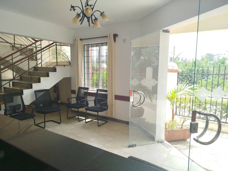A hotel lobby with a staircase, seating area, and a large window with a view of greenery.