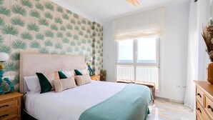 Une chambre à coucher avec un lit, un ventilateur de plafond, une fenêtre avec des rideaux et une table de chevet avec une lampe.